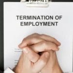 man with clasped hands over termination of employment document